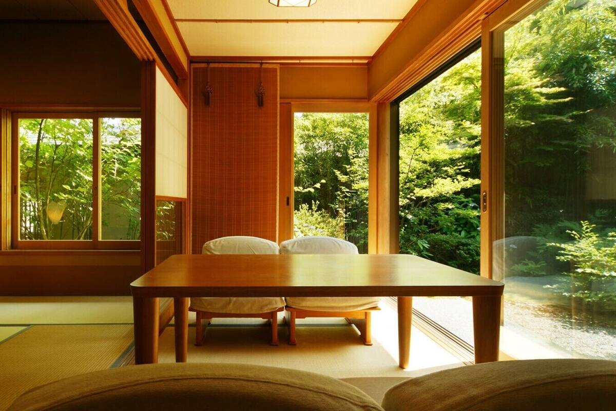 A traditional Japanese room with tatami flooring, a low table, and a sliding door leading to a garden.