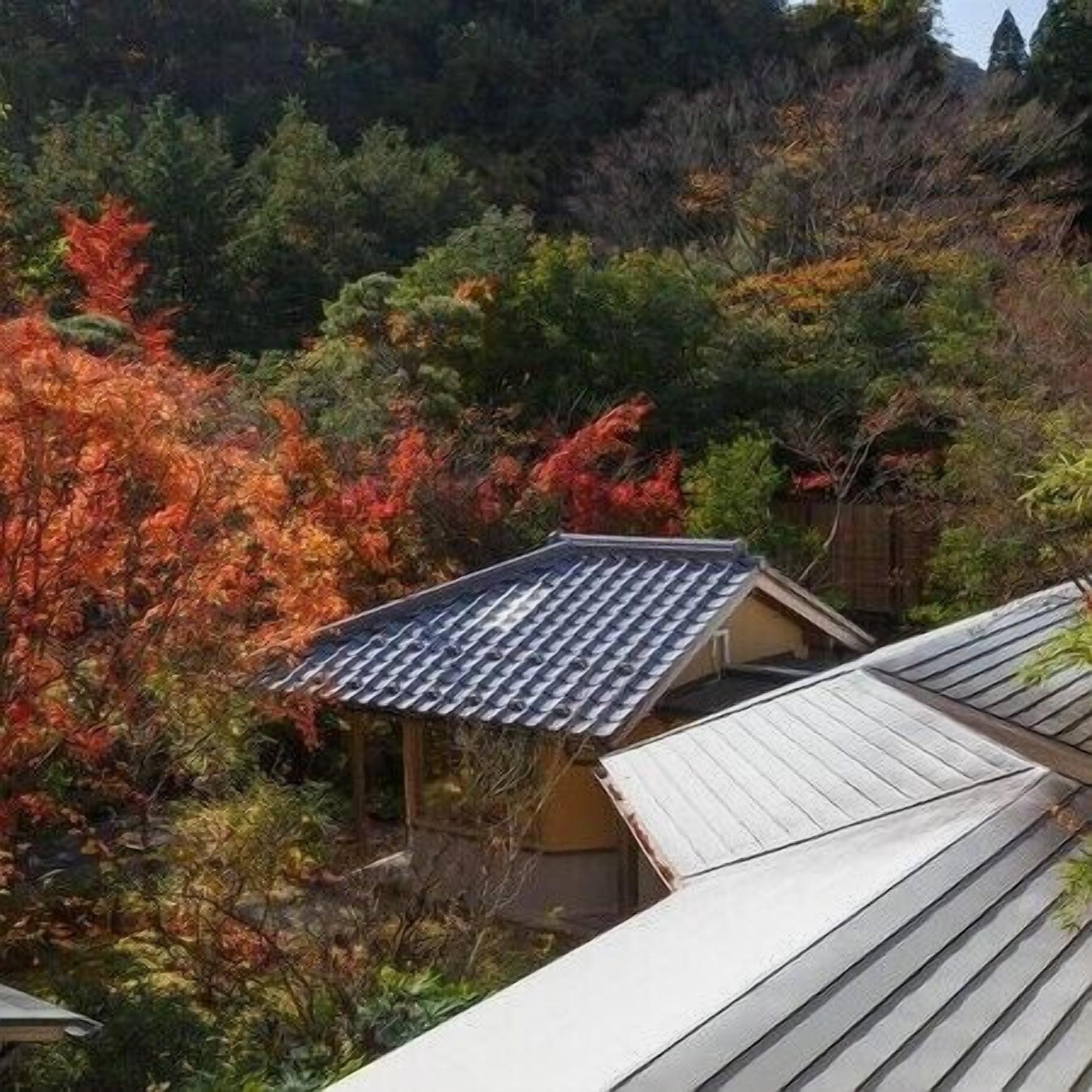 A traditional Japanese-style building with a sloped roof, surrounded by autumn foliage.