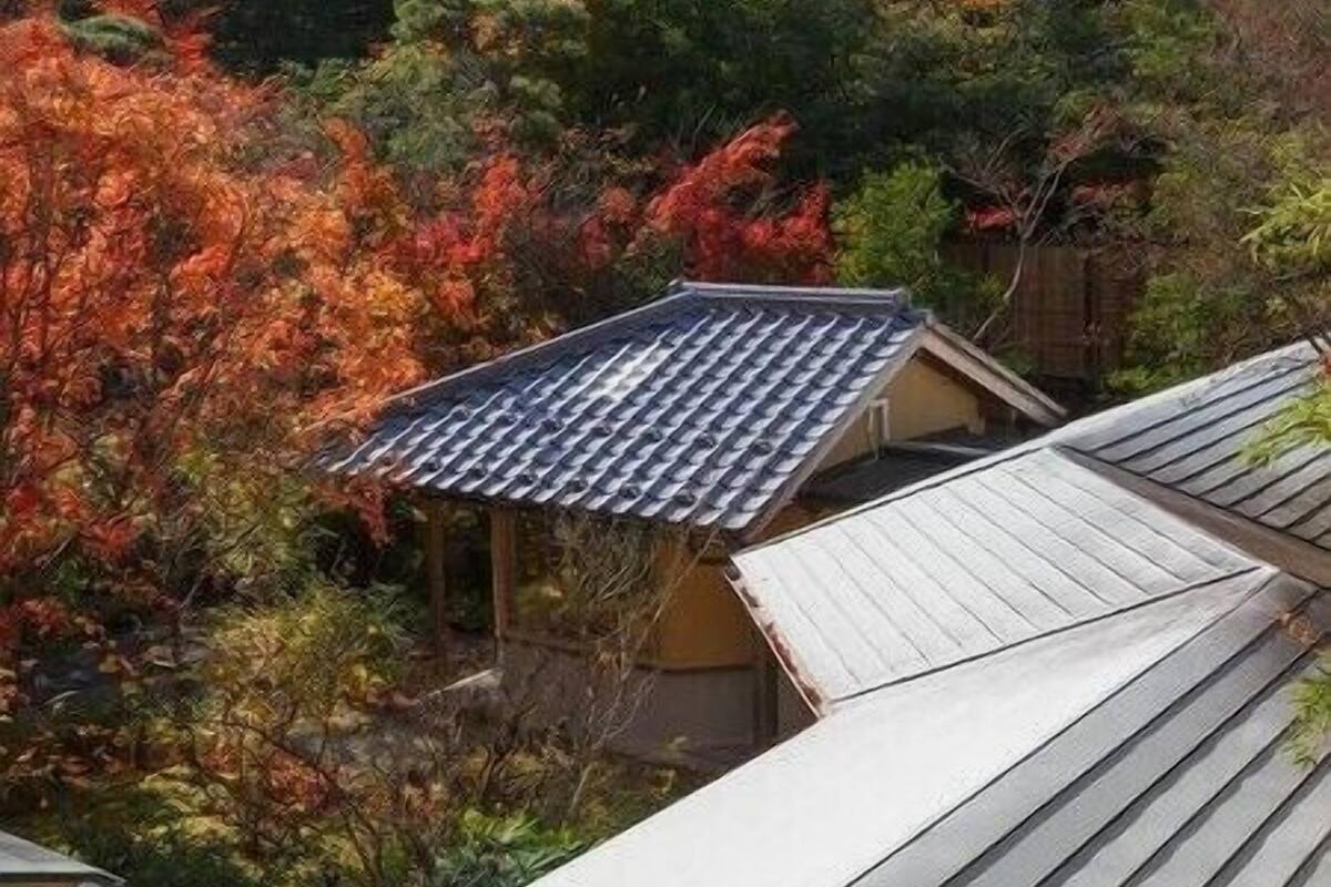 A traditional Japanese-style building with a sloped roof, surrounded by autumn foliage.
