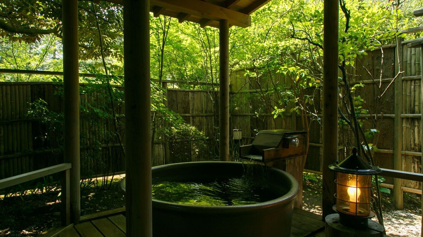 A covered outdoor area with a hot tub, a grill, and a lantern.