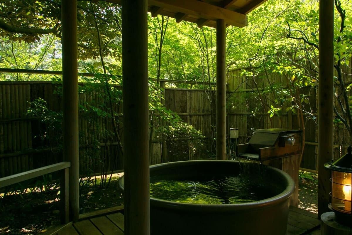A covered outdoor area with a hot tub, a grill, and a lantern.