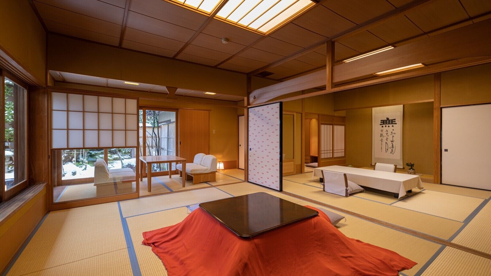 Une pièce de style japonais traditionnel, avec un sol recouvert de tatamis, une table en tatami, une petite table en bois, des portes coulissantes et une vue par la fenêtre.