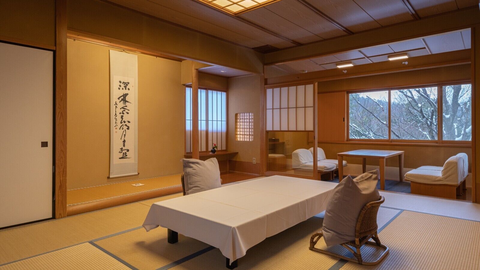 Une pièce de style japonais traditionnel, avec un sol recouvert de tatamis, une table basse, un lit et des portes coulissantes.