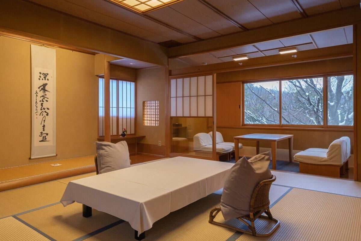 A traditional Japanese room with tatami flooring, a low table, a bed, and sliding doors.
