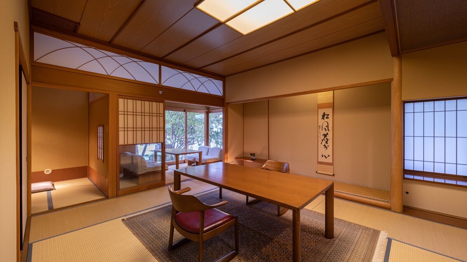 Une pièce de style japonais traditionnel, avec un sol recouvert de tatamis, une petite table en bois et une porte coulissante donnant sur un balcon.