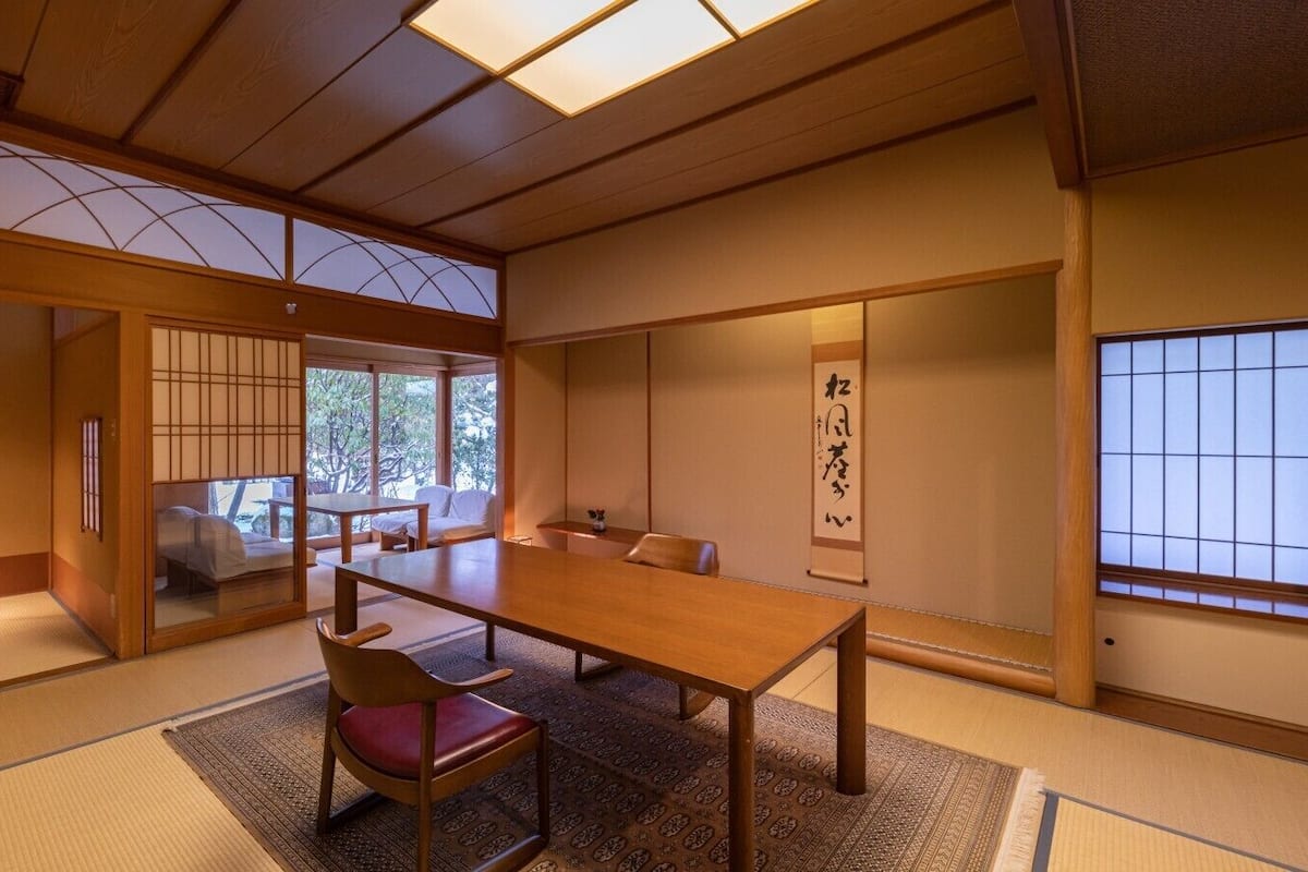A traditional Japanese room with tatami flooring, a low wooden table, and a sliding door leading to a balcony.