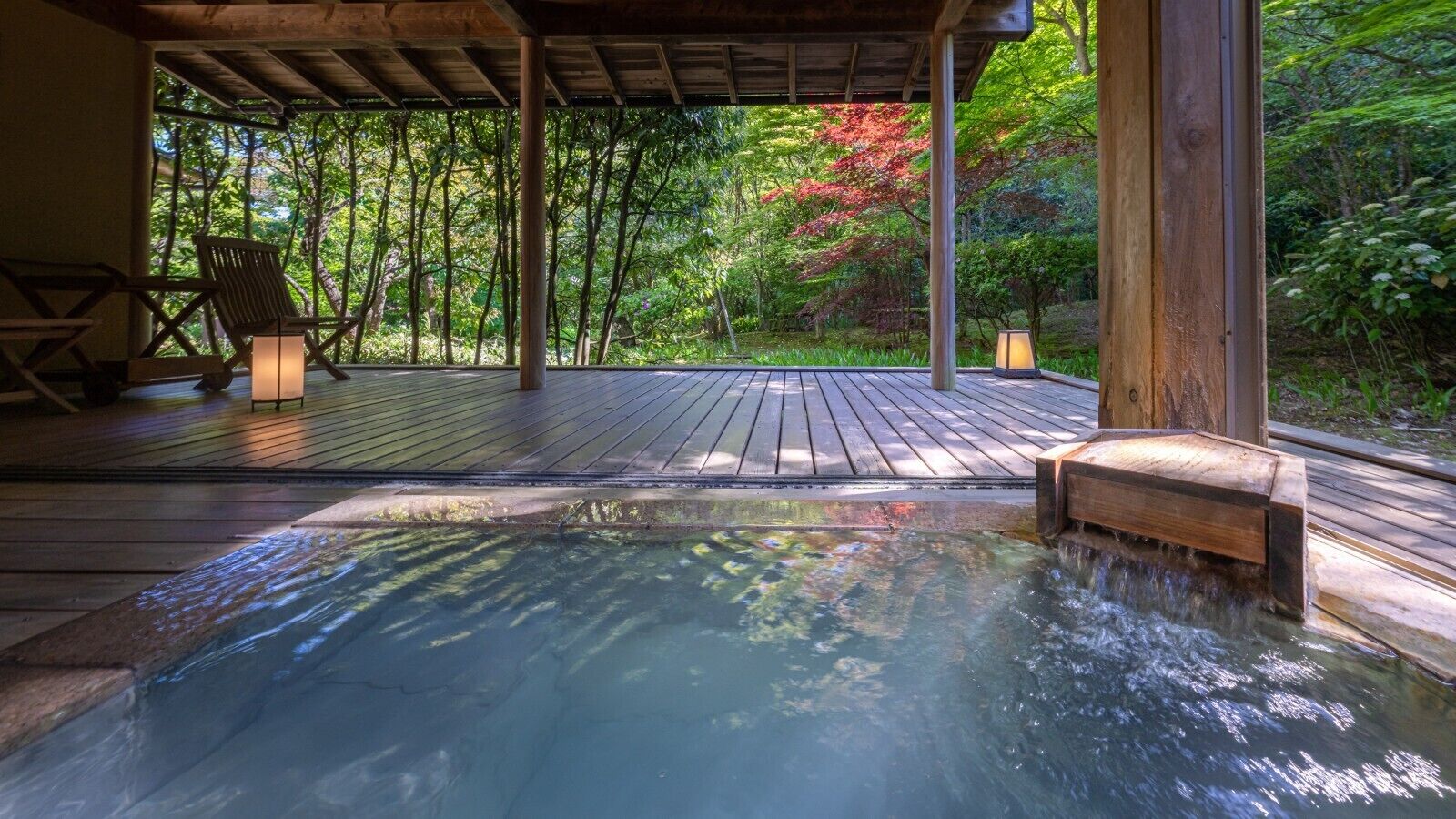A hot tub on a wooden deck with a view of a forest.
