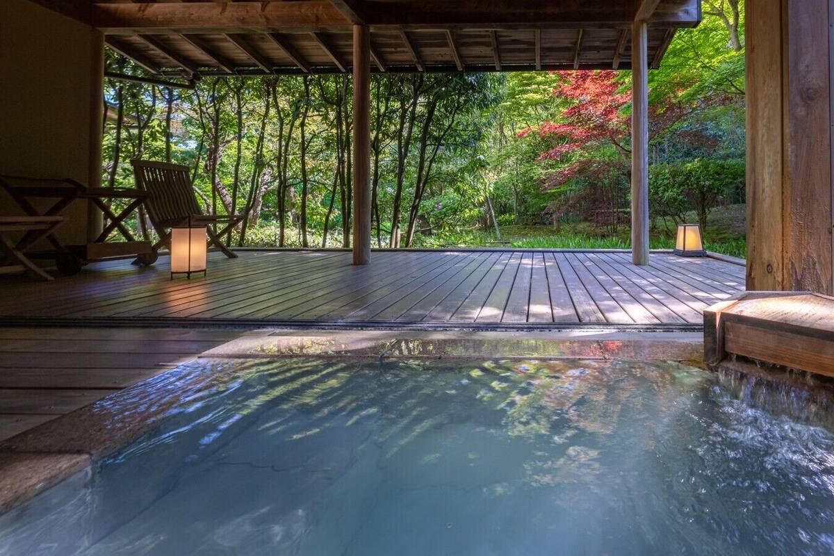 A hot tub on a wooden deck with a view of a forest.