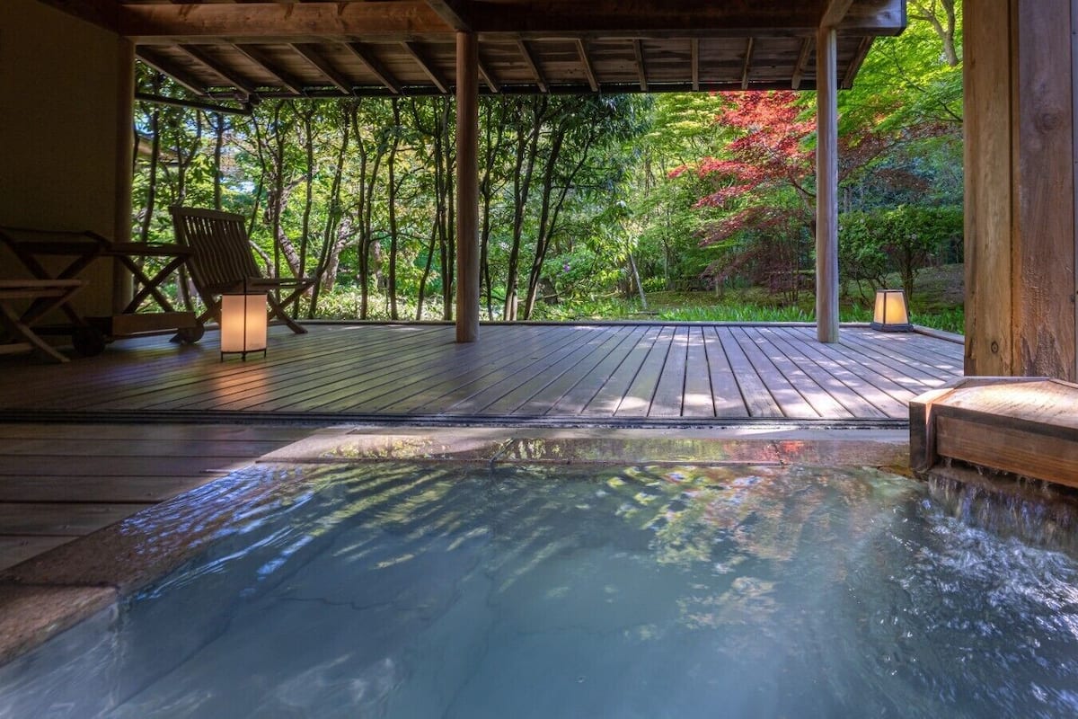 A hot tub on a wooden deck with a view of a forest.