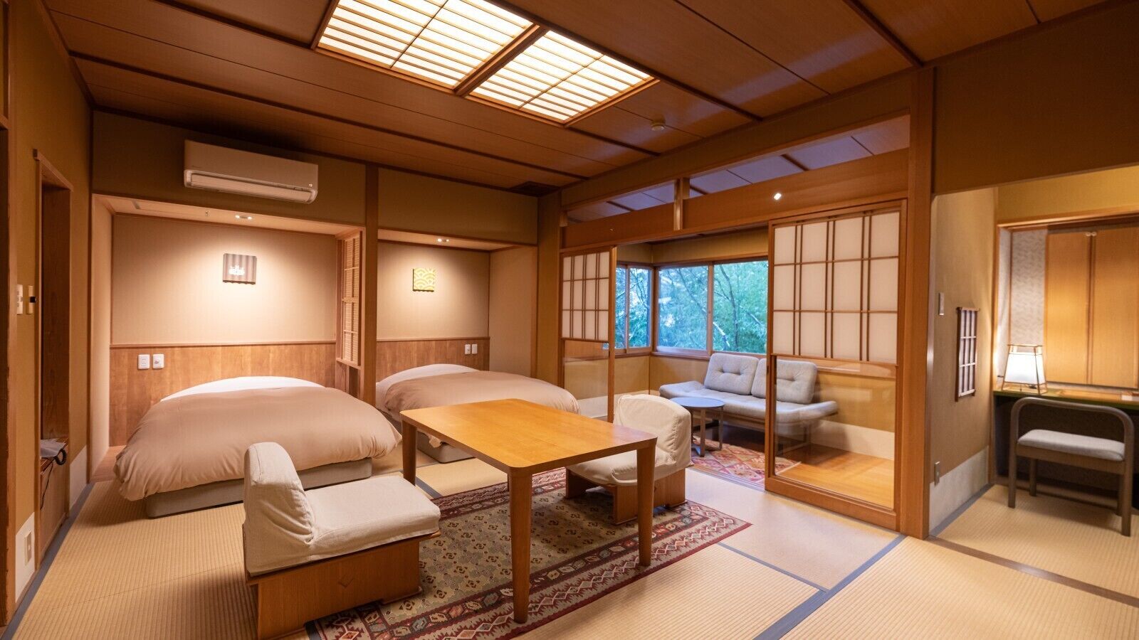 Une pièce de style japonais traditionnel, avec un sol recouvert de tatamis, une table basse, un canapé et des portes coulissantes.