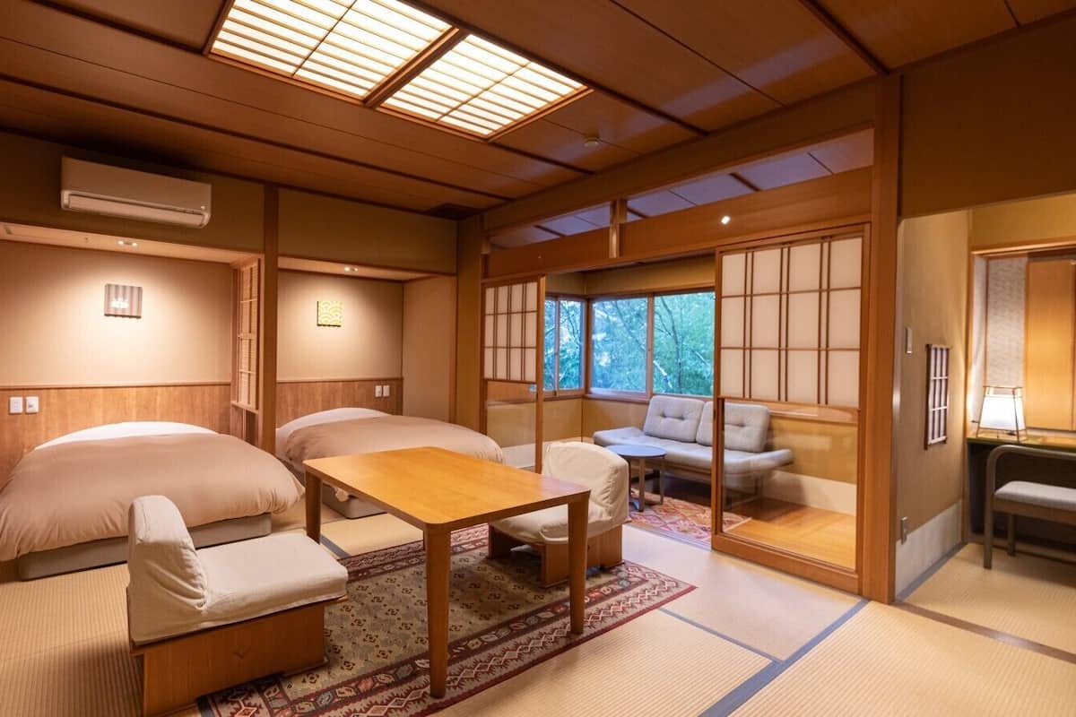 A traditional Japanese-style room with tatami flooring, a low table, a sofa, and sliding doors.