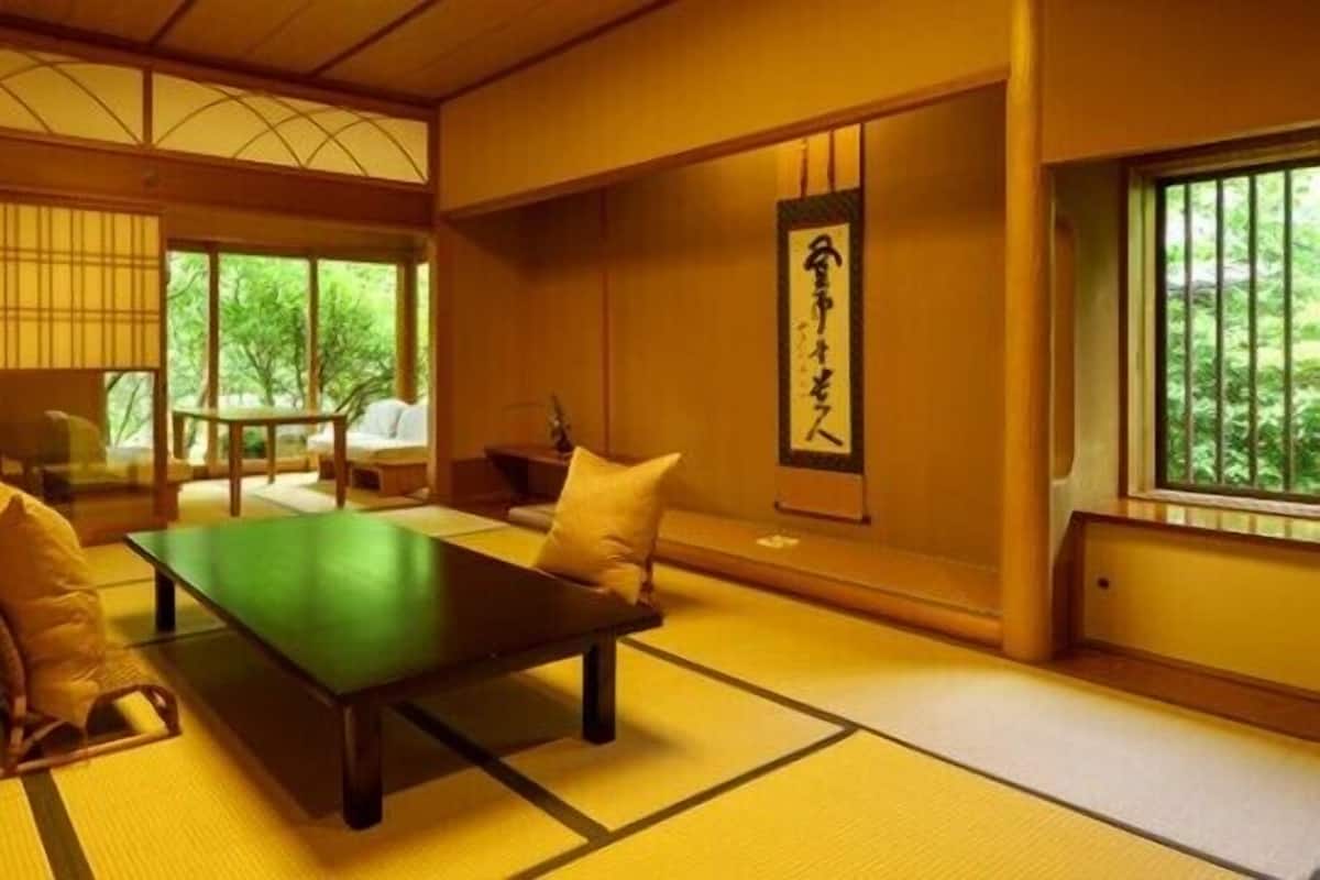 A traditional Japanese room with tatami flooring, a low table, cushions, and a sliding door leading to a garden.