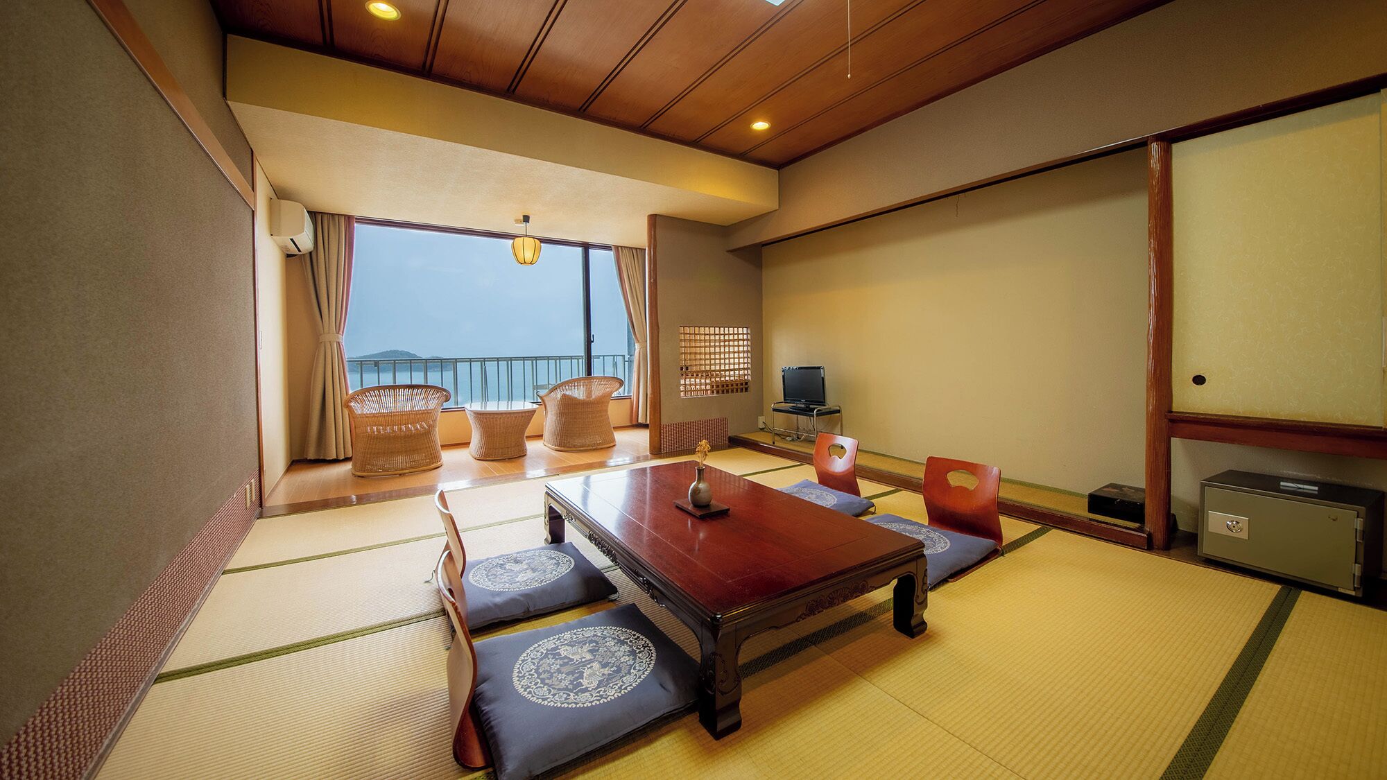 Una habitación tradicional japonesa con suelo de tatami, una mesa de madera baja y vista al mar.