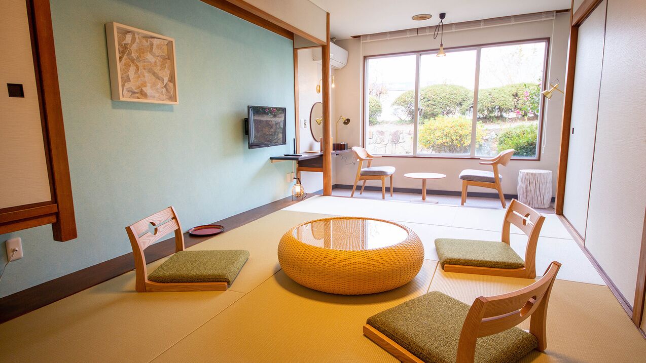 Una habitación tradicional japonesa con suelo de tatami, una mesa baja y sillas de madera.