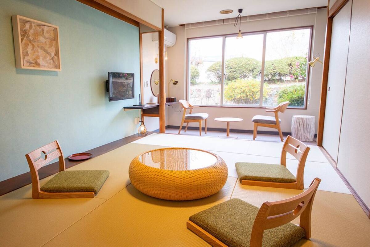 A traditional Japanese-style room with tatami flooring, a low table, and wooden chairs.
