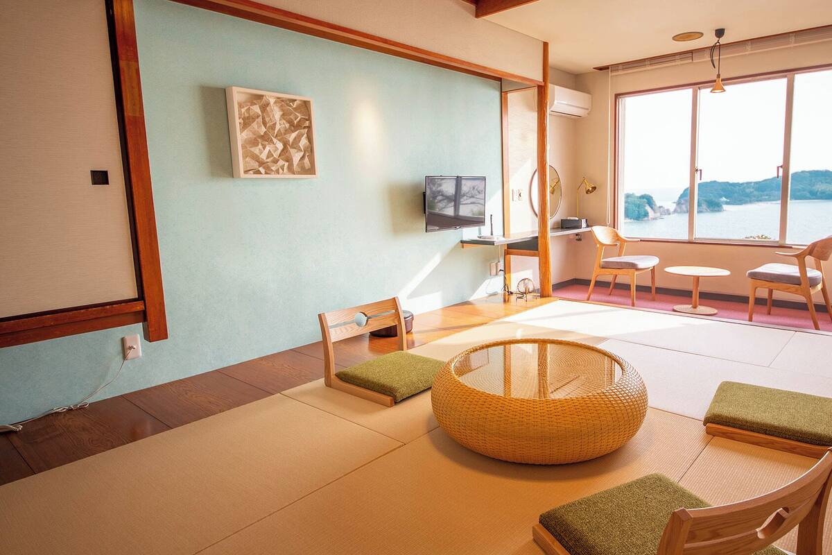 A traditional Japanese-style room with tatami flooring, a low table, and a view of the sea.