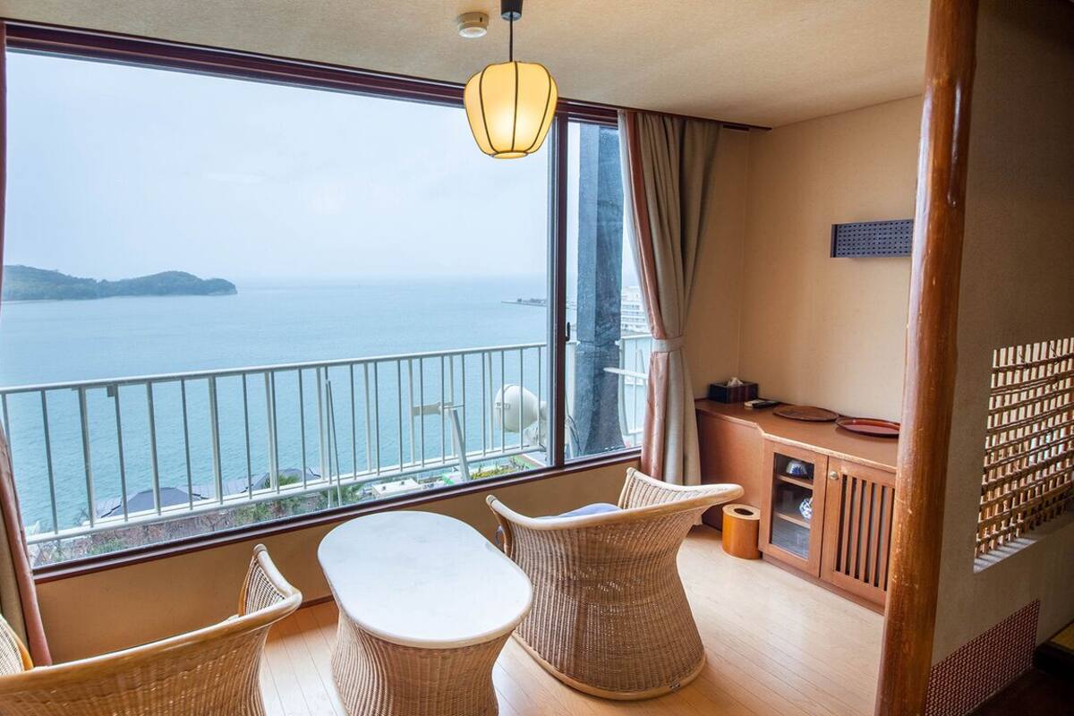 A balcony with a view of the sea, wicker furniture, and a small table.