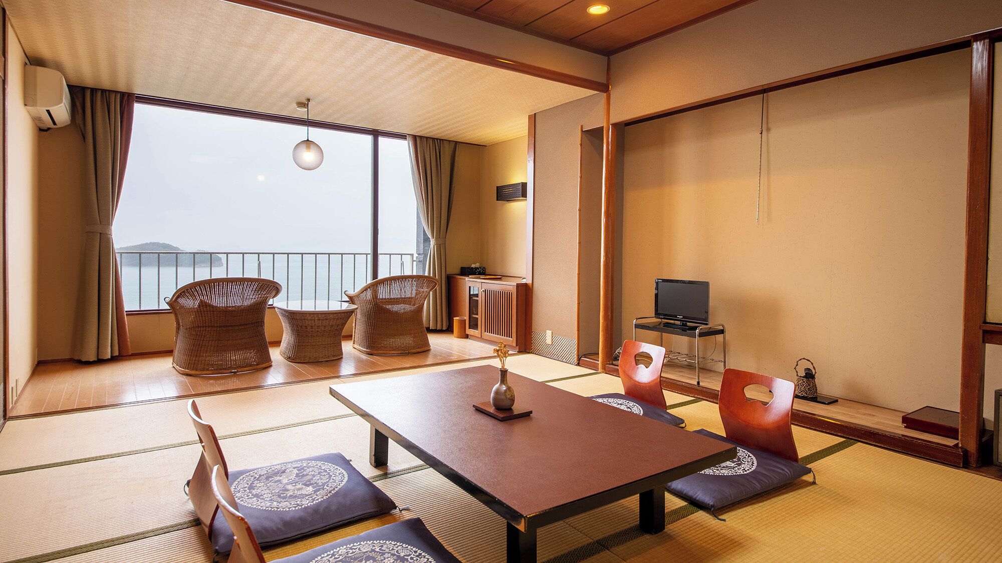 Una habitación japonesa tradicional con suelo de tatami, una mesa baja y un televisor sobre un mueble.