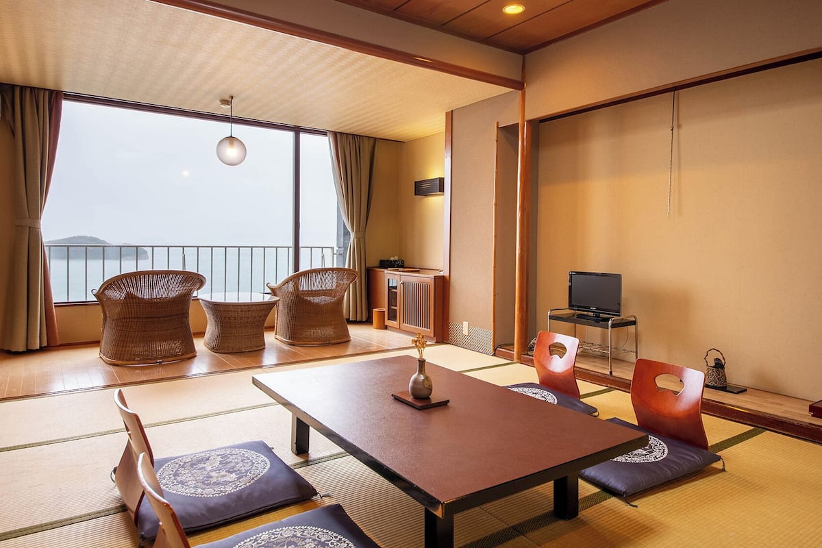 A traditional Japanese room with tatami flooring, a low table, and a TV on a stand.