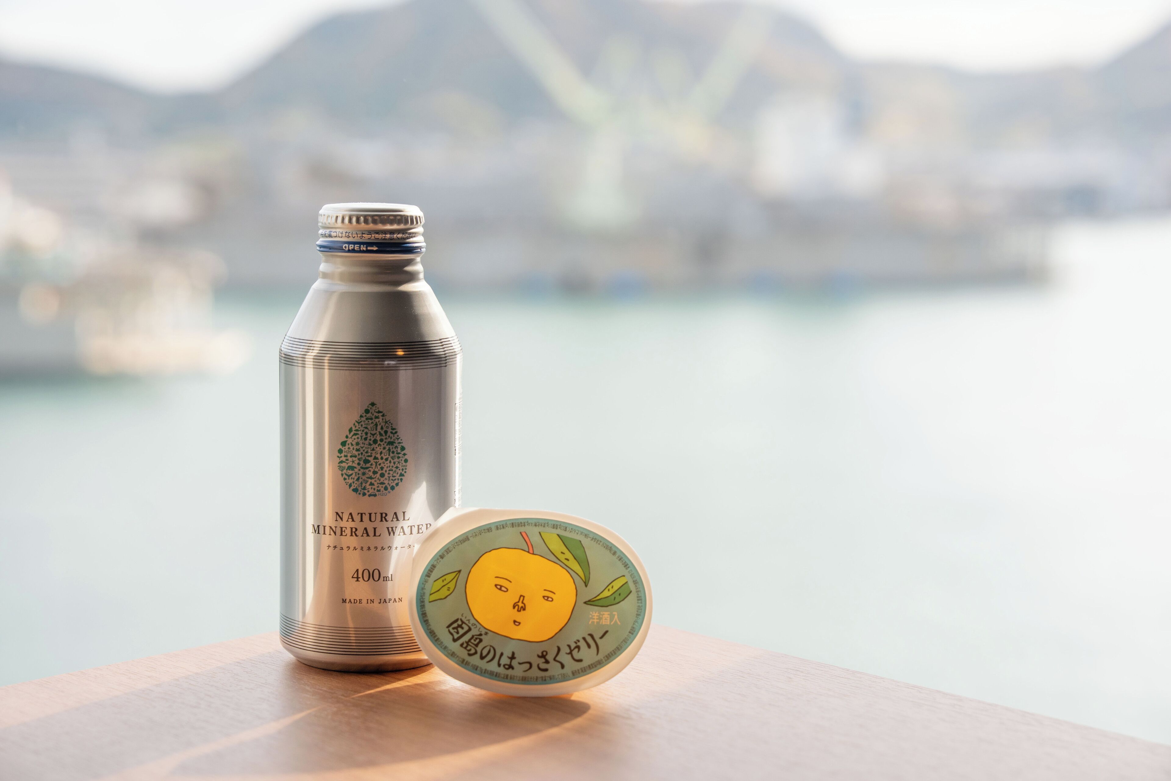 A stainless steel water bottle and a container with a lemon design on a wooden surface.