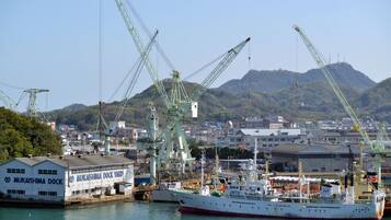 A large cargo ship docked at a port with cranes and industrial buildings in the background.