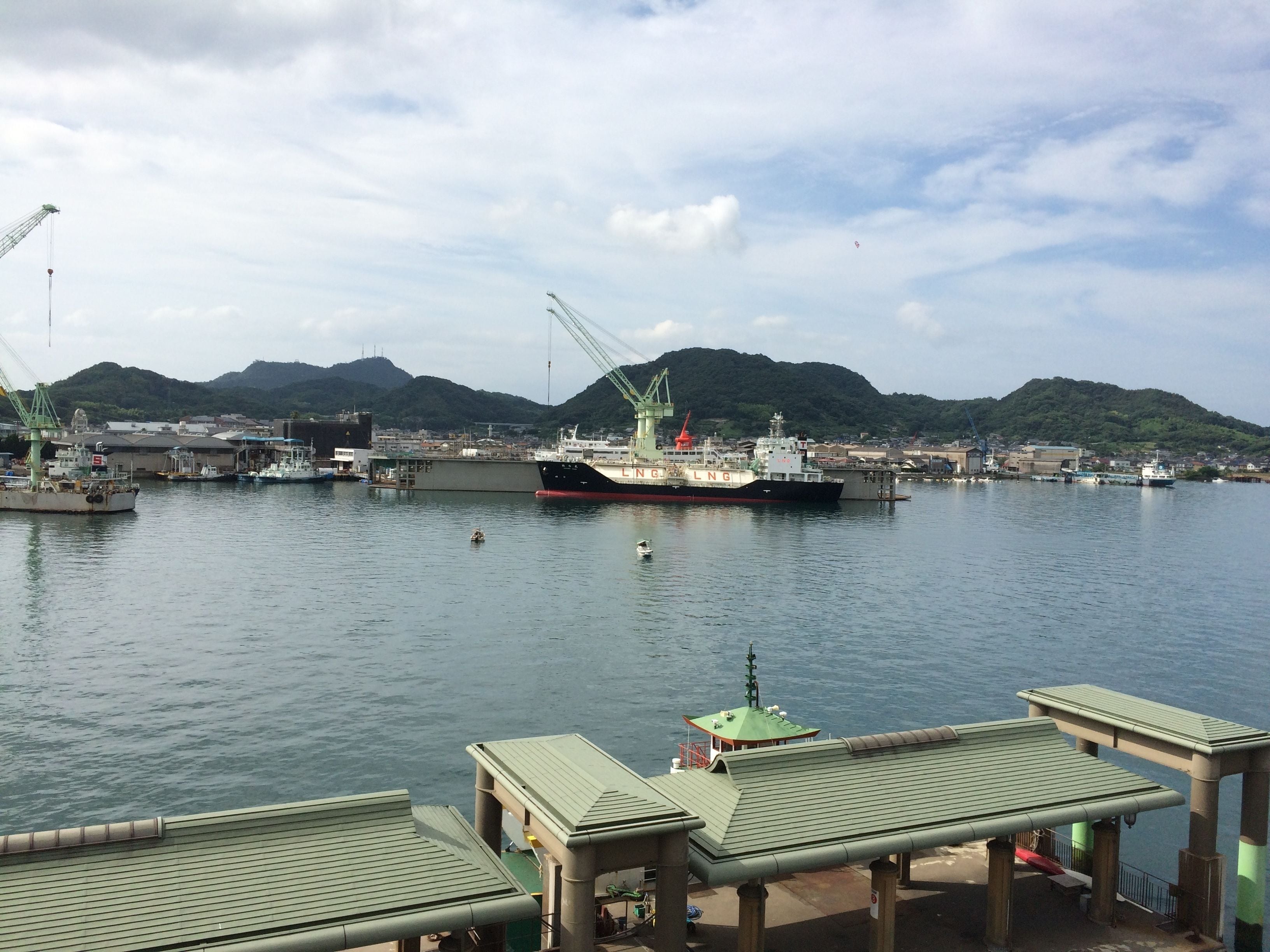 A harbor with boats, cranes, and a mountainous backdrop.