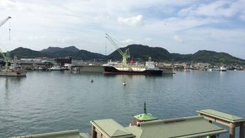 A harbor with boats, cranes, and a mountainous backdrop.