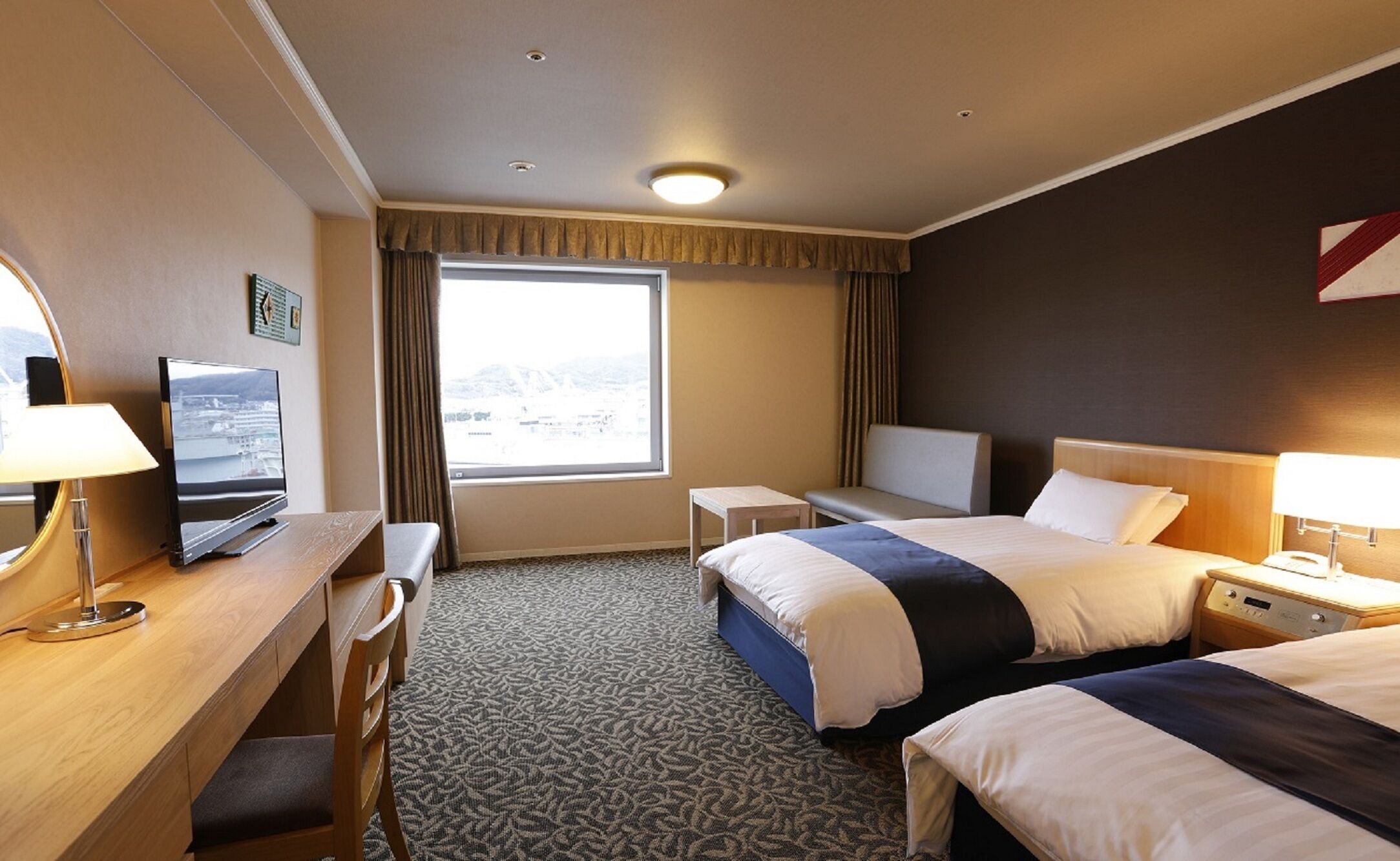 Ein Hotelzimmer mit Bett, Schreibtisch, Stuhl und Fernseher.