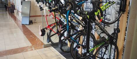 Una estación de alquiler de bicicletas con varias disponibles y un cartel que indica la dirección a la entrada.