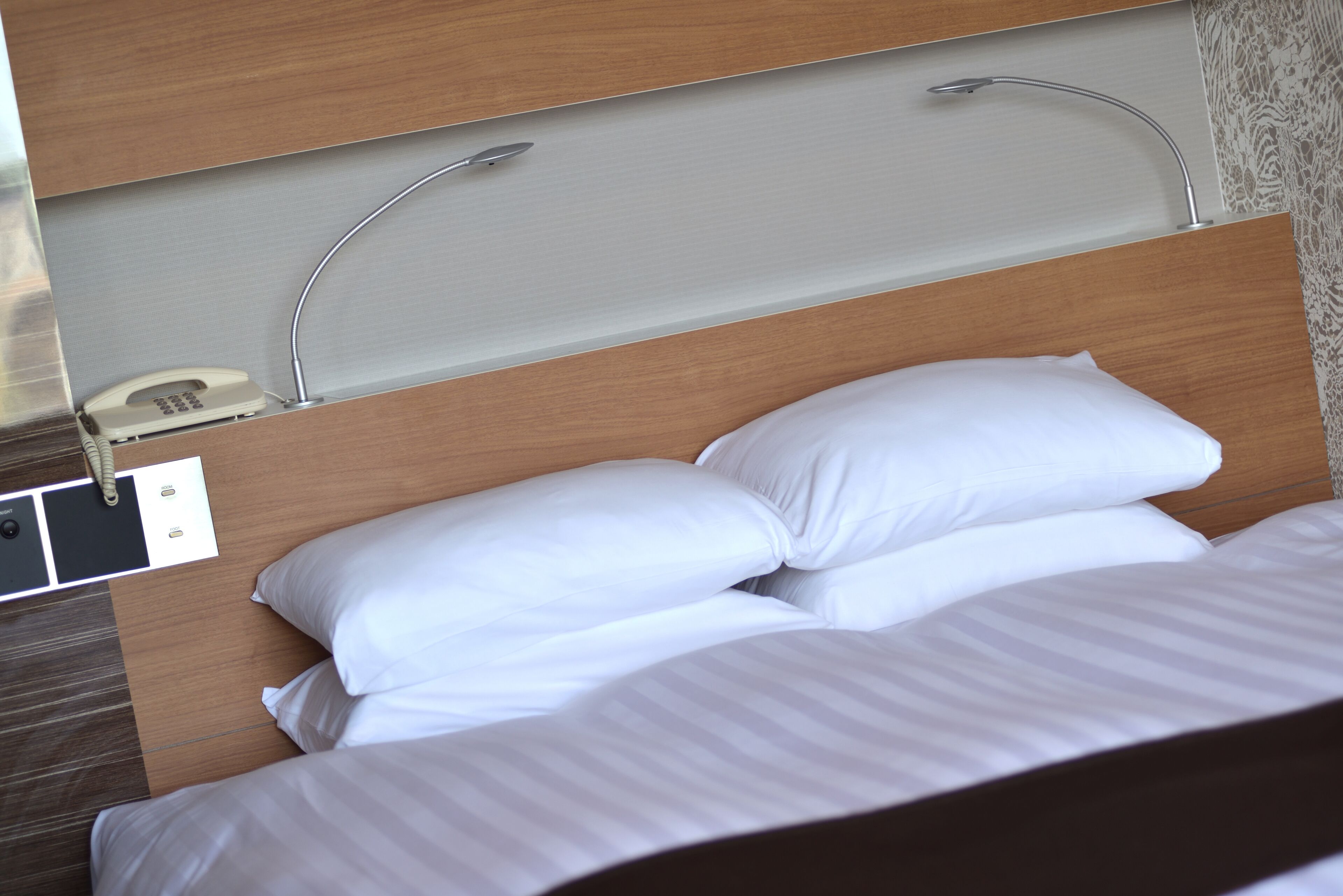 Una cama bien hecha con ropa de cama blanca y un cabecero con iluminación integrada.