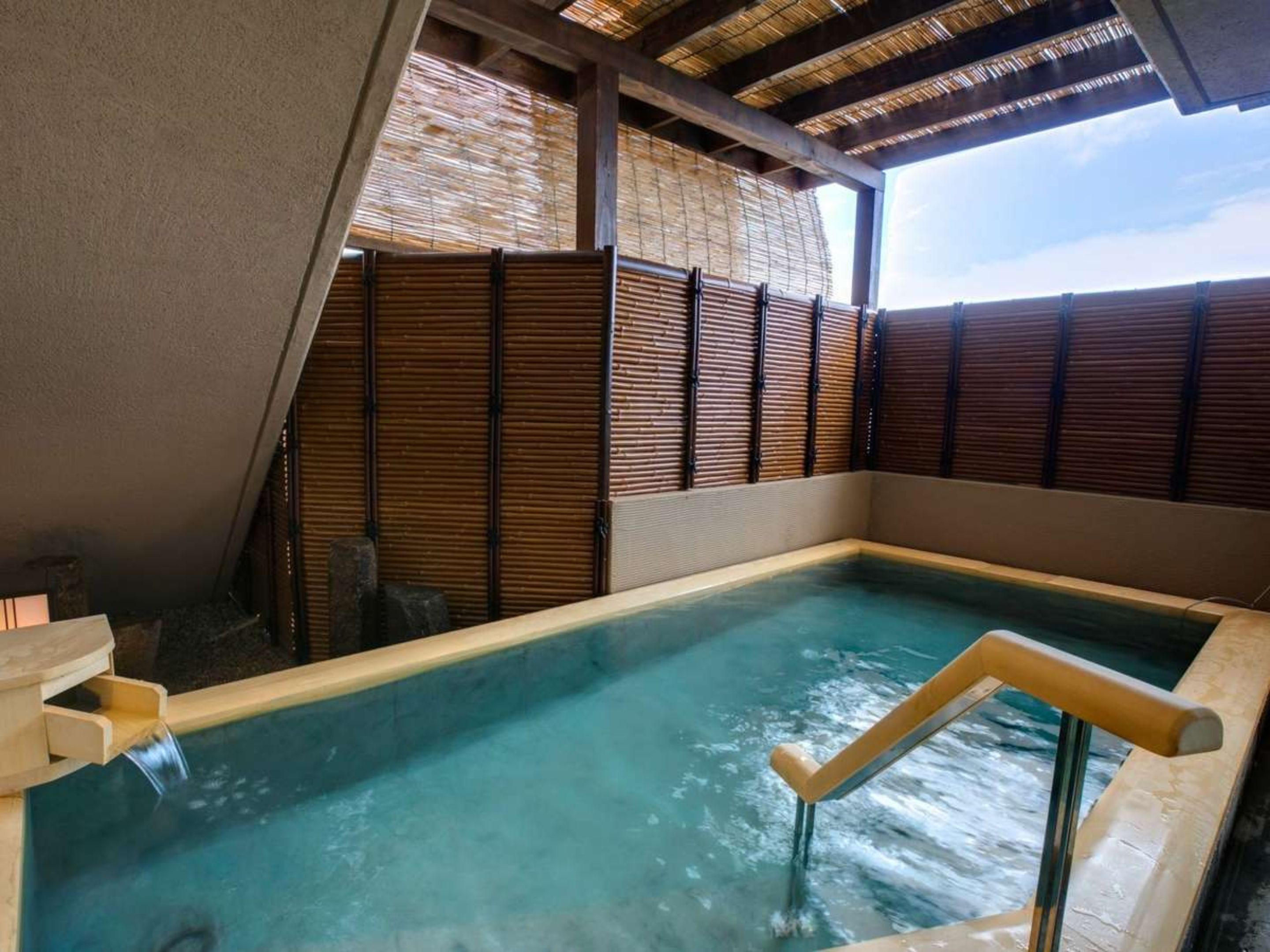 A hot spring bath with wooden railings and a bamboo wall.