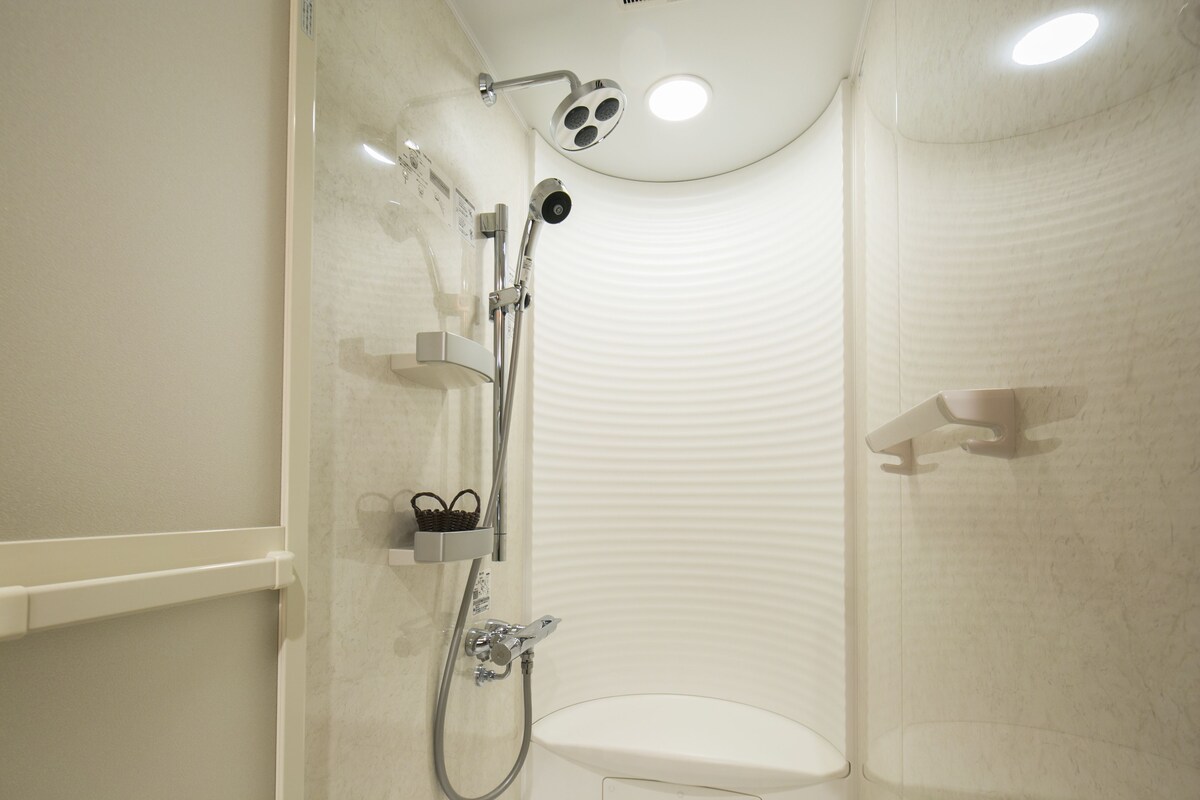 Un baño moderno con ducha, inodoro y un pequeño estante con una cesta.