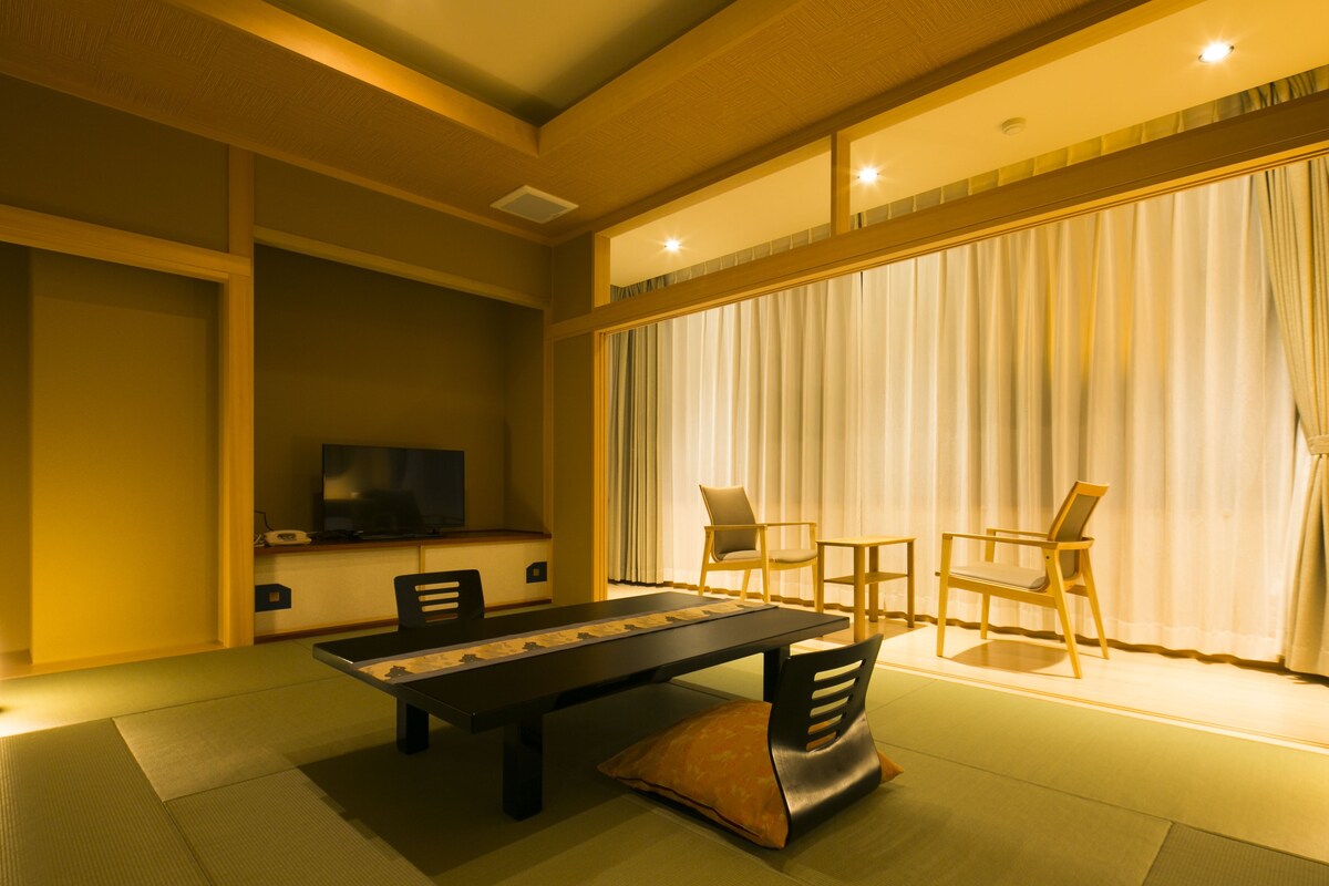 A traditional Japanese-style room with tatami flooring, a low table, and a television.