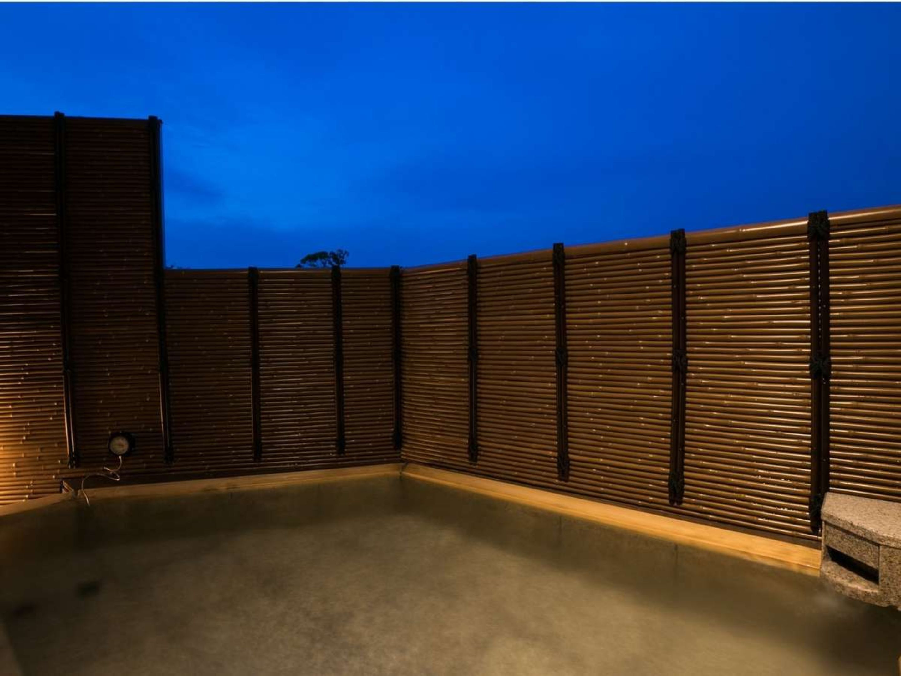 A rooftop pool area with a wooden fence and a concrete floor.