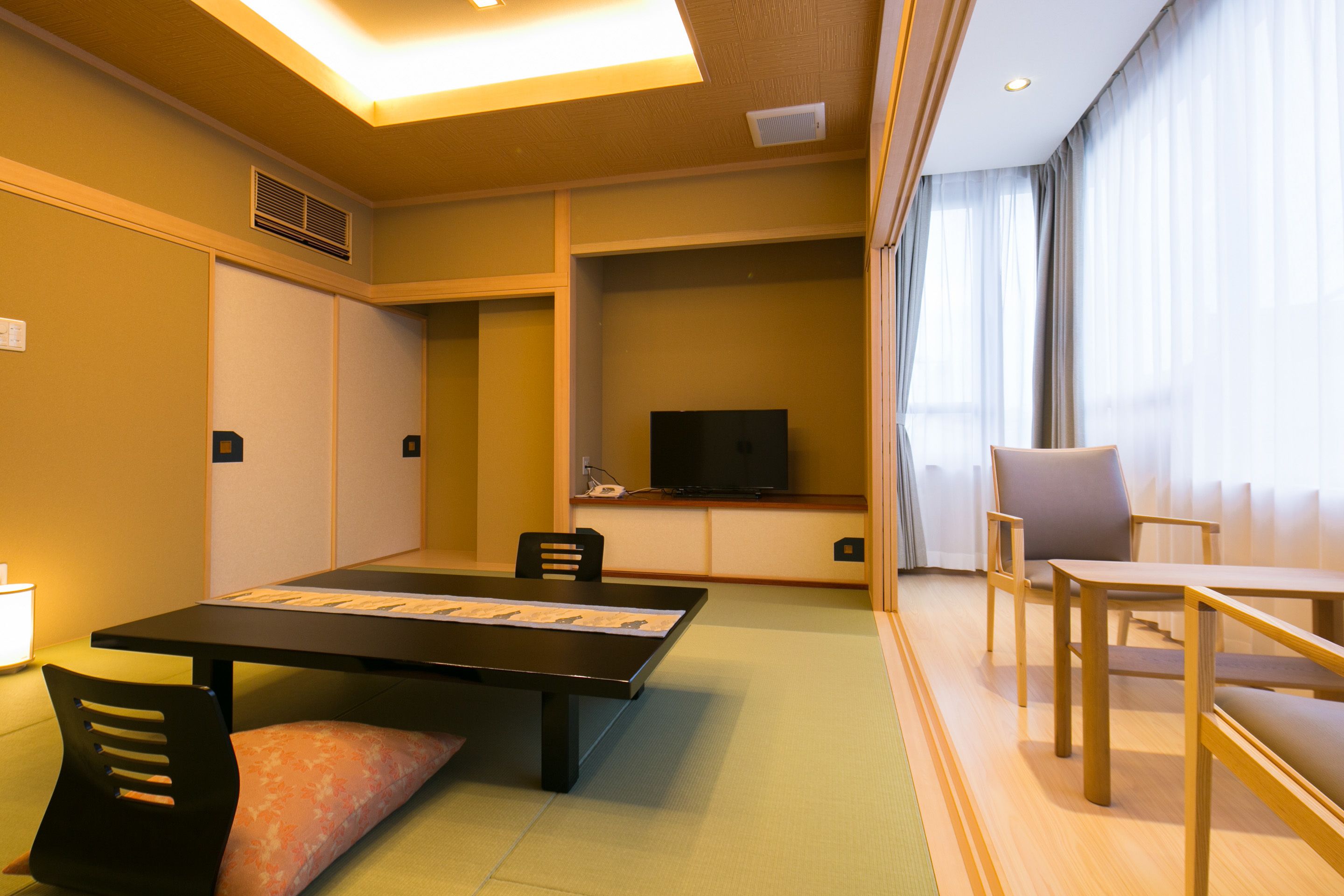 Habitación de hotel con una mesa de comedor, sillas, televisor y sofá.