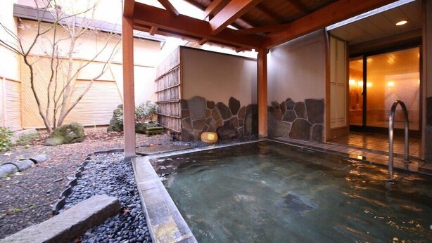 A hot spring area with a stone wall, wooden beams, and a tiled floor. - Kawaguchiko Park Hotel (FUJIKAWAGUCHIKO)