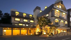 A multi-story hotel with a modern architectural design, featuring large windows and a well-lit entrance. - Kawaguchiko Park Hotel (FUJIKAWAGUCHIKO)