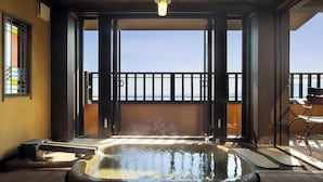 Un jacuzzi en un balcón con vistas al mar, una silla y una mesita.