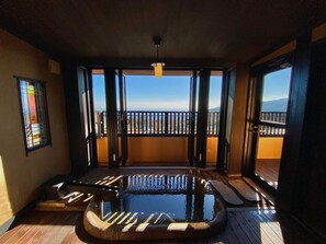 Una stanza con pavimento in legno, un piccolo elemento d'acqua, una finestra con vista e una porta che dà su un balcone esterno.