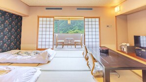 A traditional Japanese-style room with tatami flooring, a low table with chairs, a bed with a futon, and a television on a wooden stand. - Hotel Secondstage (Takamatsu)
