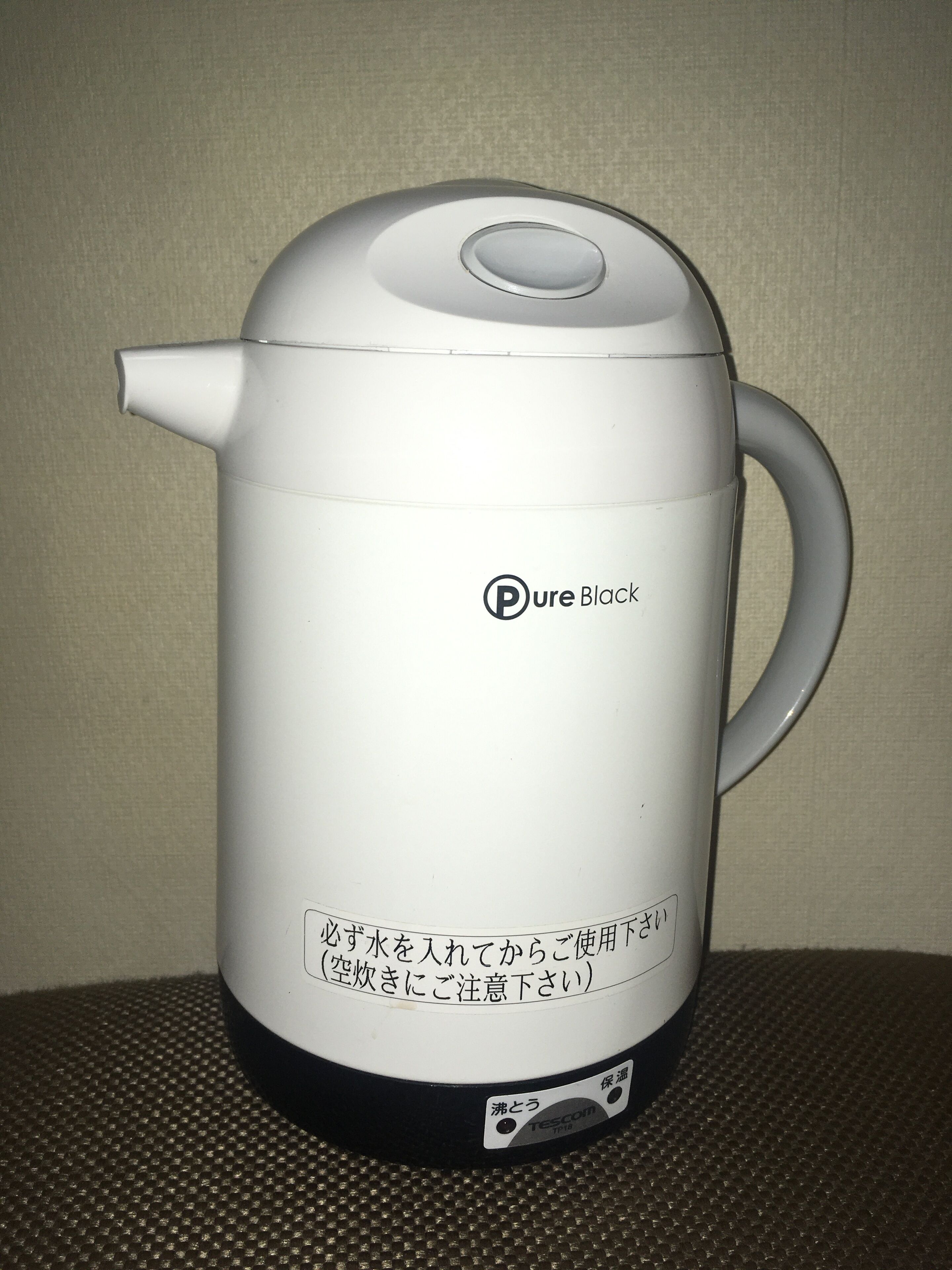 A white electric kettle with a handle and a control button, labeled "Pure Black."