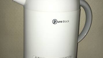 A white electric kettle with a handle and a control button, labeled "Pure Black."