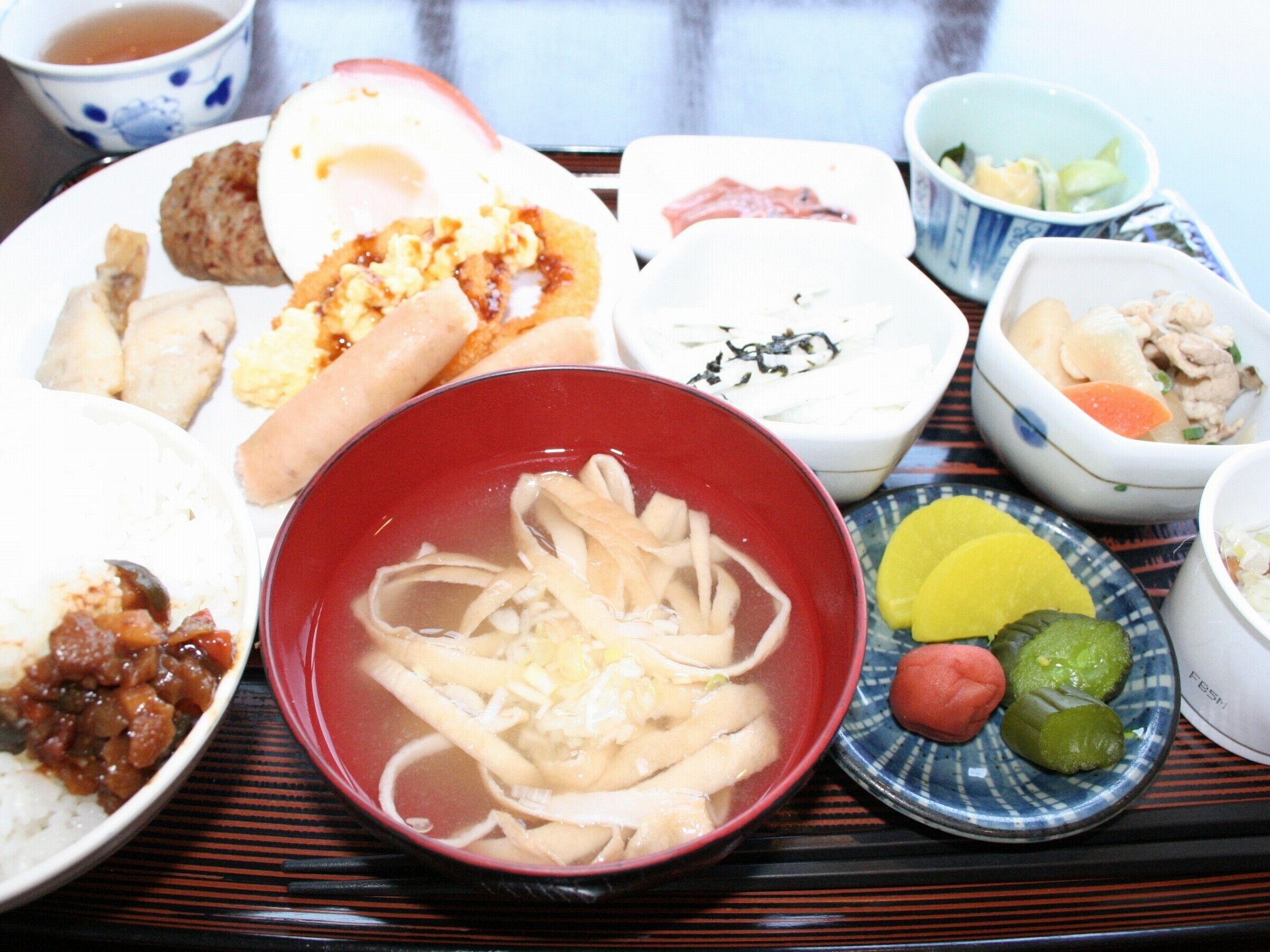 A variety of Japanese dishes on a tray, including rice, noodles, and several small bowls with different sauces and sides.