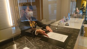 A person seated at a counter with a document in front of them, a payment terminal, and a small Christmas tree decoration in the background. - Smile Hotel Hachinohe (Hachinohe)