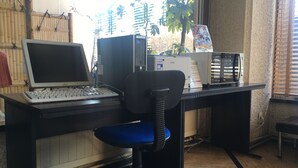 A computer desk with a laptop, desktop computer, and printer. There is a chair with a blue cushion. - Smile Hotel Hachinohe (Hachinohe)