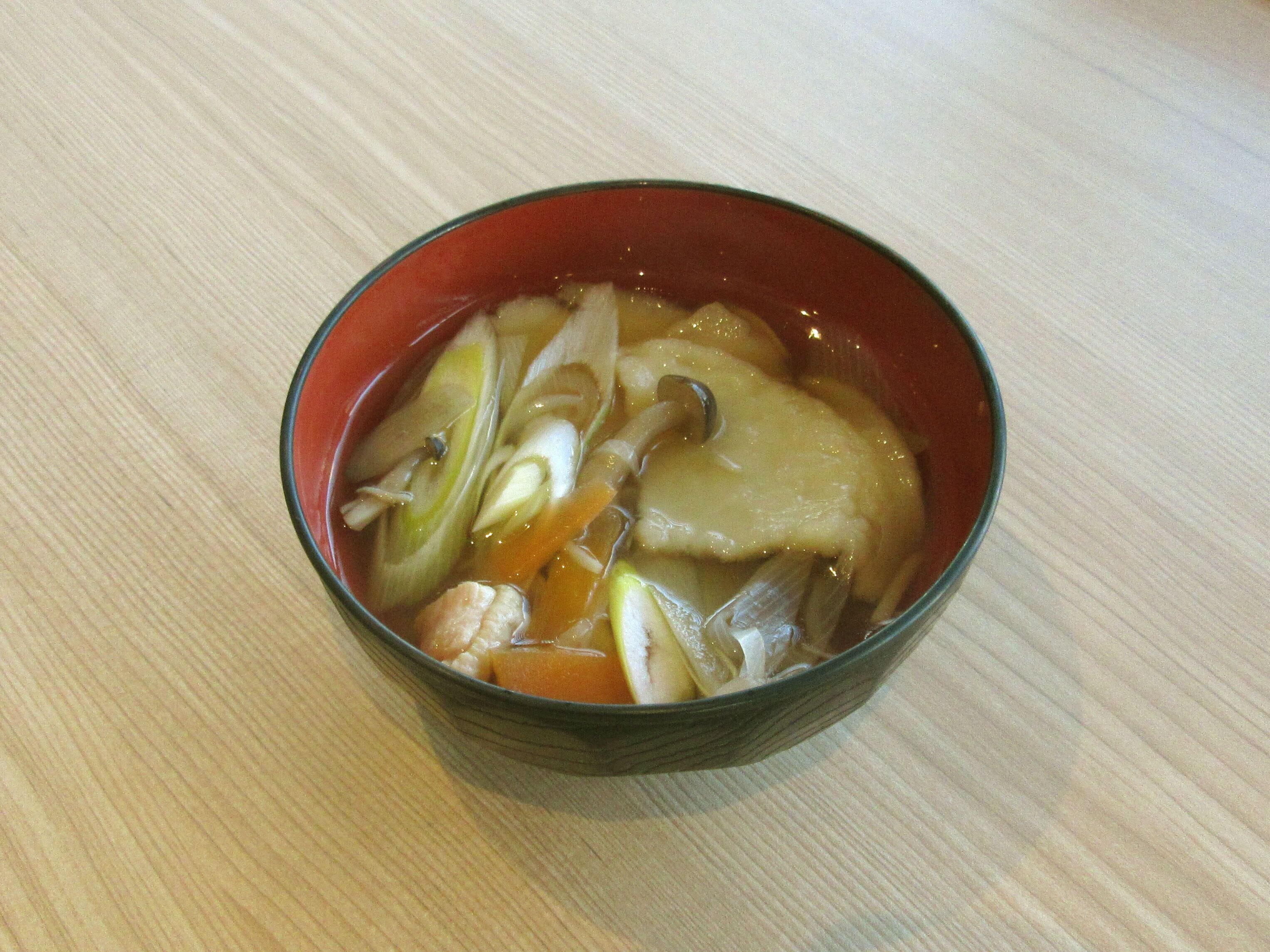 Eine Schüssel Suppe mit Gemüse und Fleisch auf einem Holztisch.