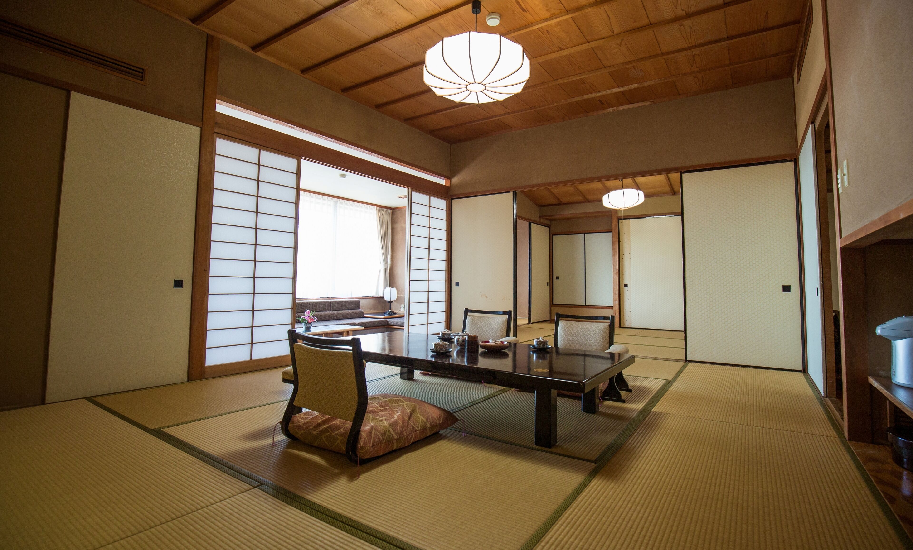 Una habitación japonesa tradicional con suelo de tatami, una mesa baja y puertas correderas.