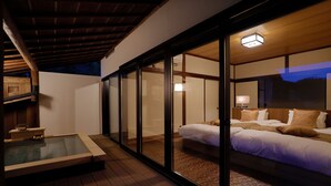 Un dormitorio moderno con una cama grande, un área con paredes de vidrio y suelo de madera.