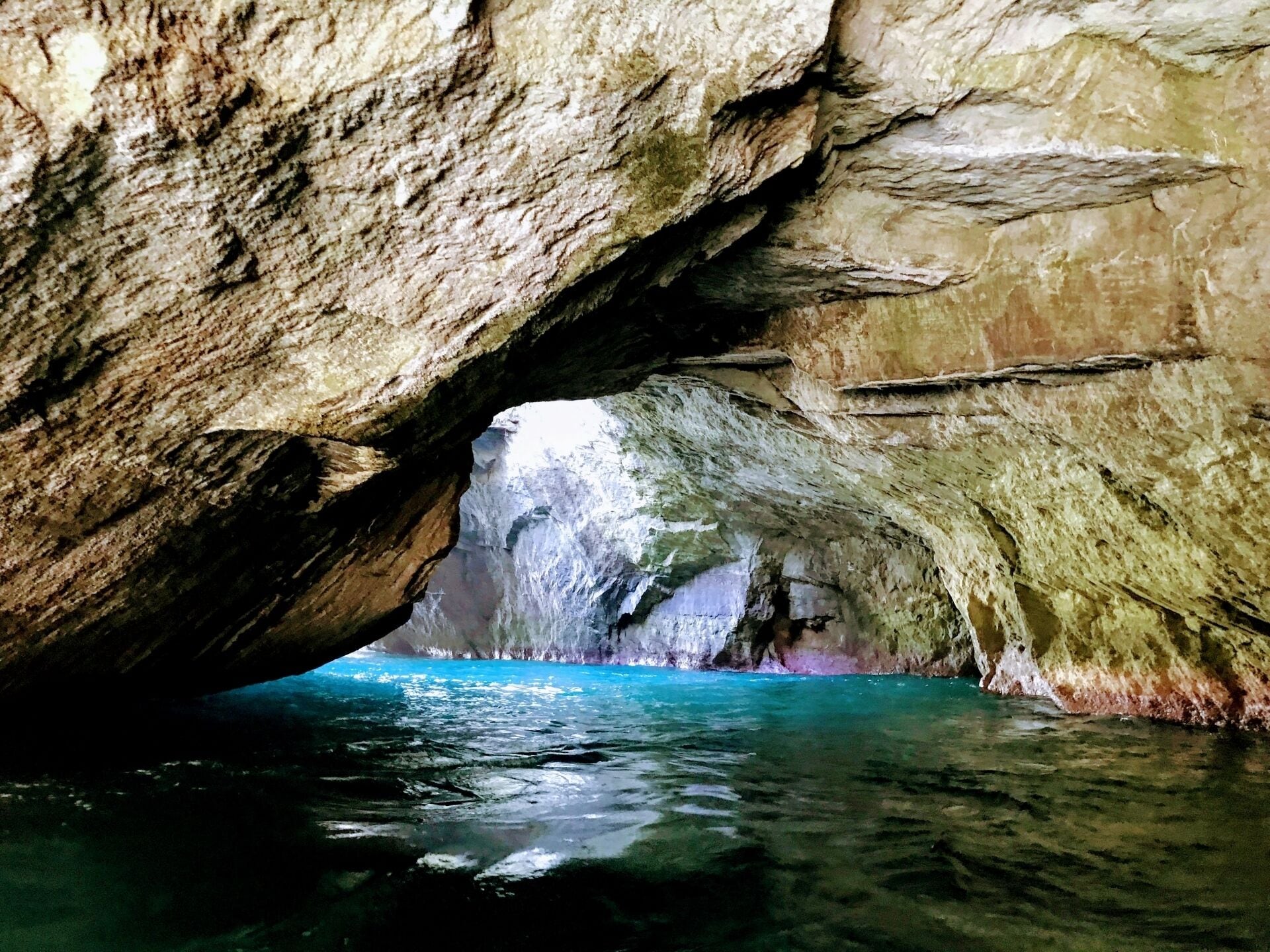 A natural rock formation with a cave opening leading to a body of water.