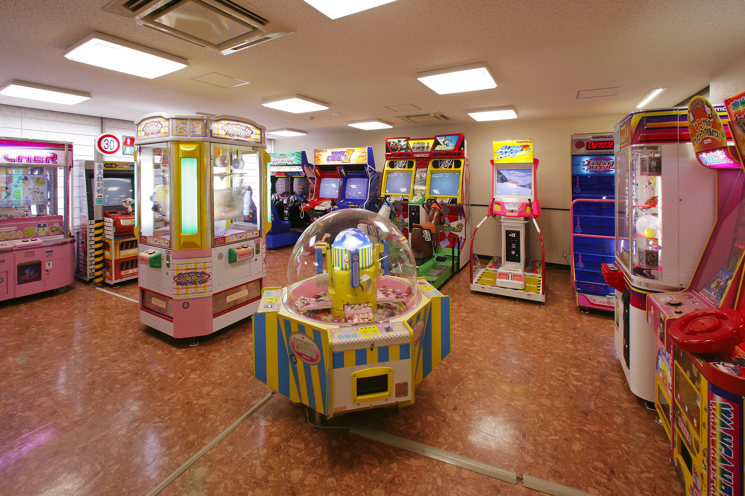 Un salón de juegos recreativos con diversas máquinas, incluyendo máquinas con pinzas y juegos de carreras.